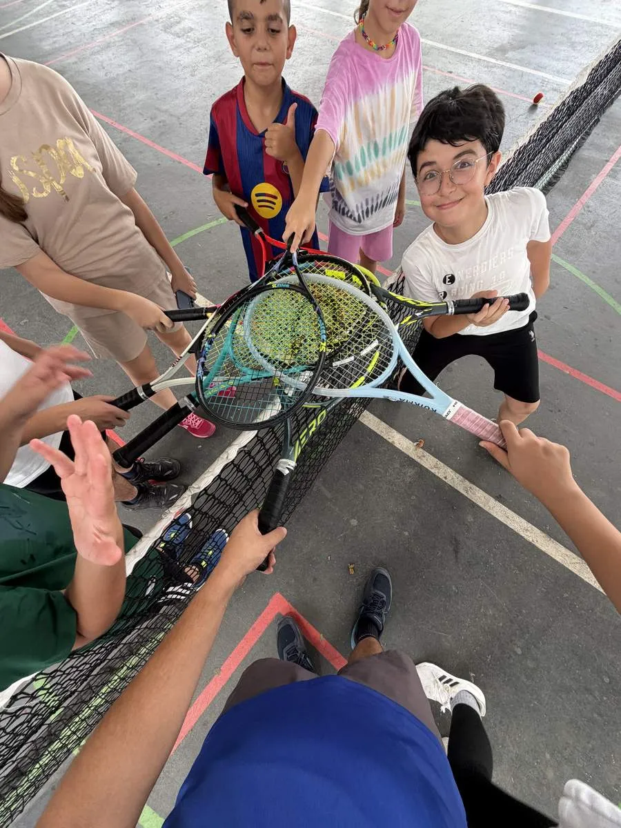 Students stacking rackets together at the net